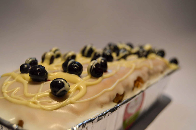 imagen de Budin de arándanos decorado con glase y arándanos con hilos de chocolate blanco